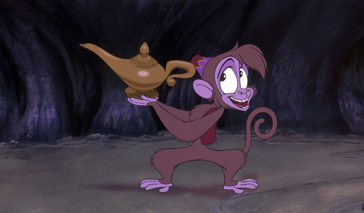 Abu, from Aladdin, is smiling and looking mischievous as he offers the magic lamp.