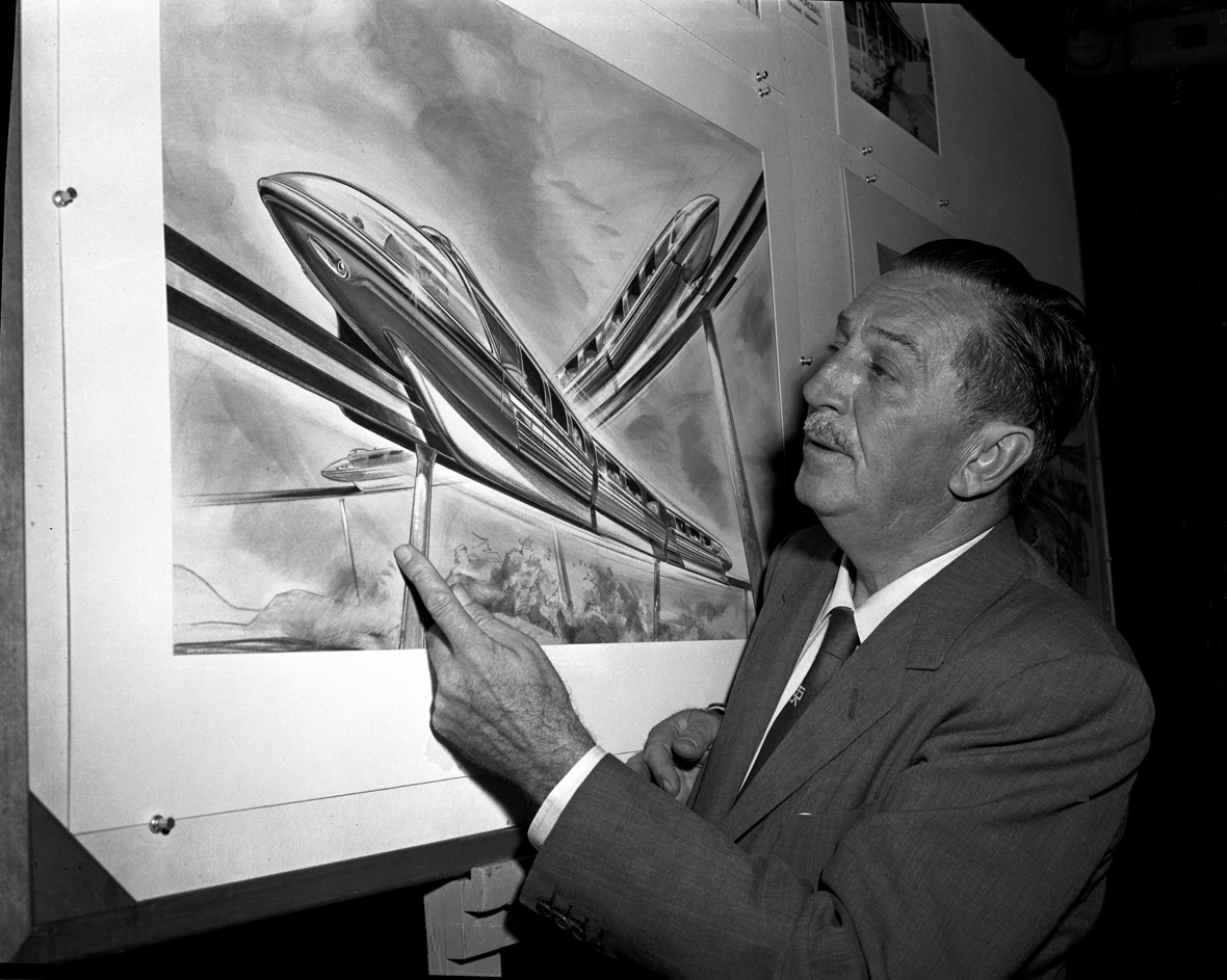 Walt Disney looks at framed Monorail plans.