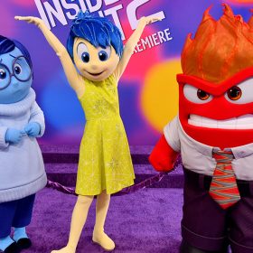 Inside Out 2 characters, left to right, Sadness, Joy, and Anger stand together in poses appropriate to their personalities at the film’s world premiere at the El Capitan Theatre in Hollywood, California, on June 10. The backdrop behind them features the film’s logo repeated in white on a multicolored background.