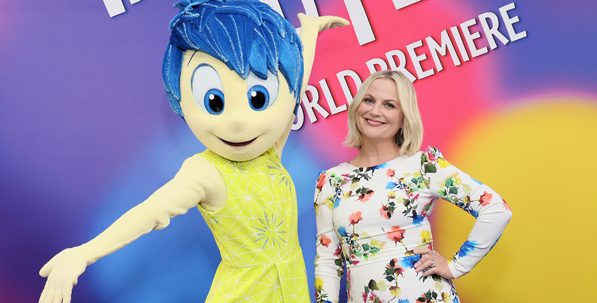Inside Out 2 cast member Amy Poehler stands next to the character Joy at the film’s world premiere at the El Capitan Theatre in Hollywood, California, on June 10. The backdrop behind them features the film’s logo in white on a multicolored background. She’s wearing a floral gown.