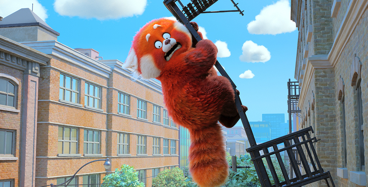 In a scene from Turning Red, Meilin “Mei” Lee, (voiced by Rosalie Chiang) transformed into a red panda, clings desperately to a railing attached to a brick building that is detaching and about to plummet to the ground. Behind the frightened red panda are similar brick buildings and a blue sky with some clouds.
