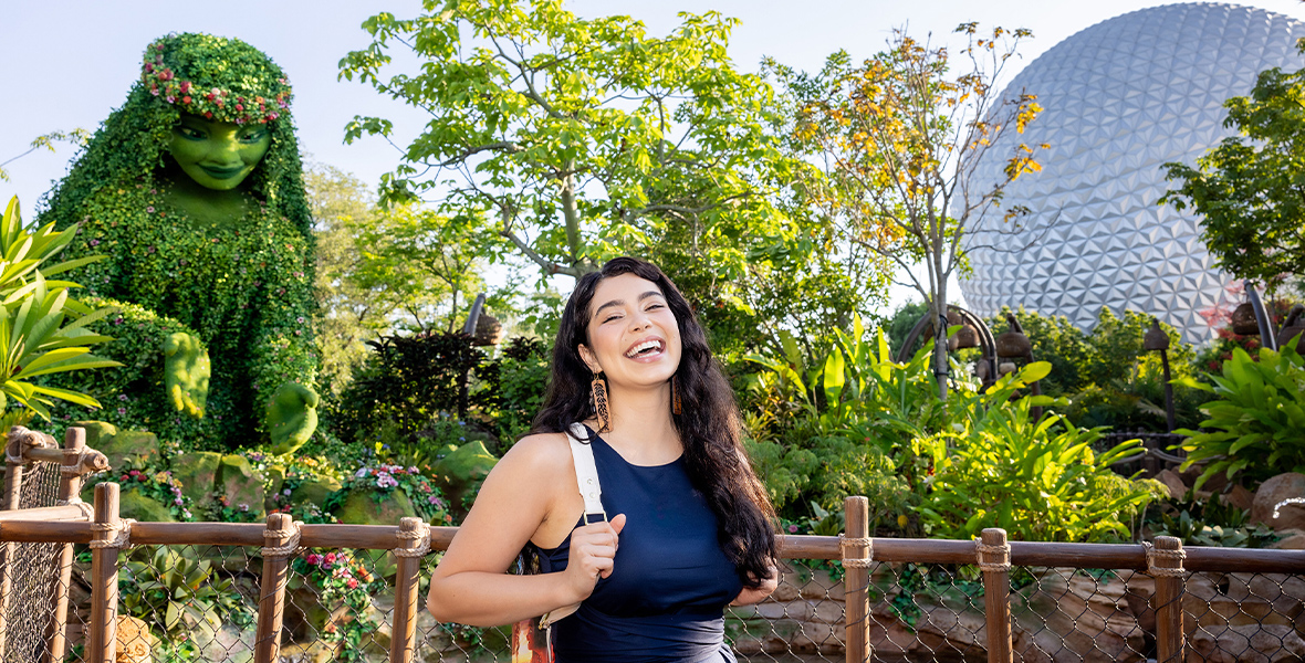 Auli'i Cravalho poses in front of Journey of Water, Inspired by Moana, at EPCOT.