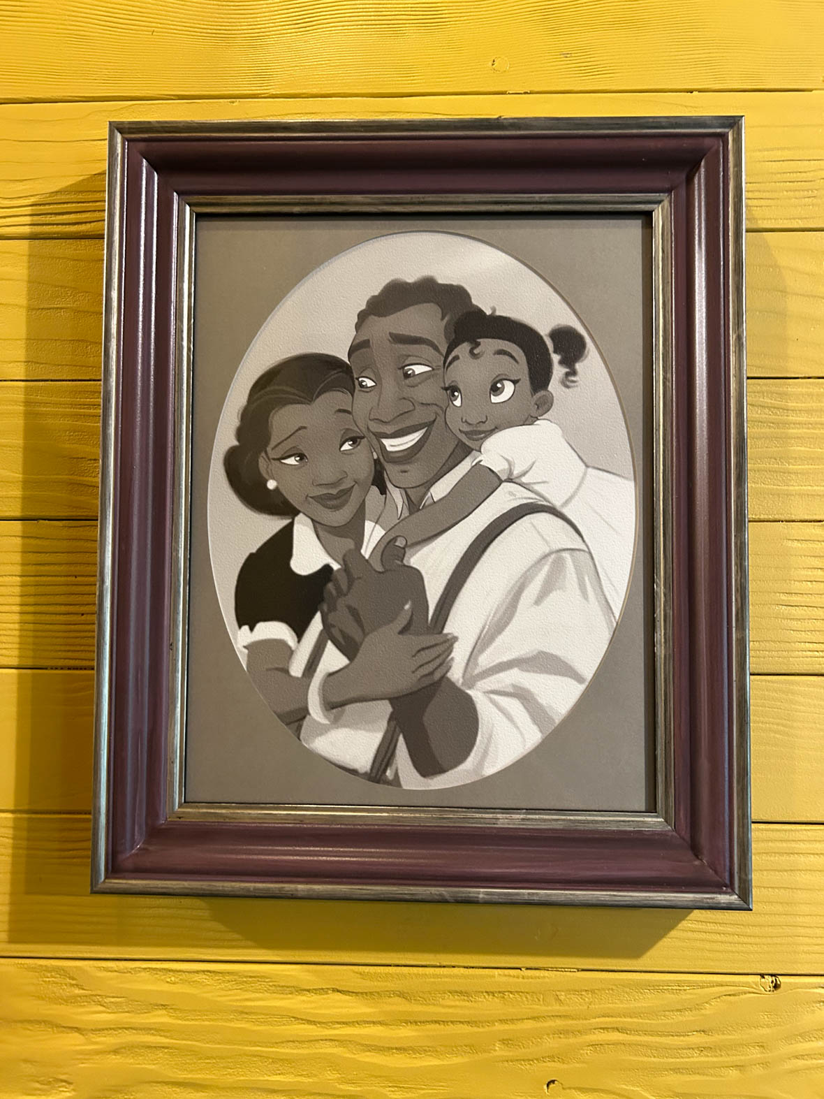 A framed black and white photo of Tiana, her father, and her mother
