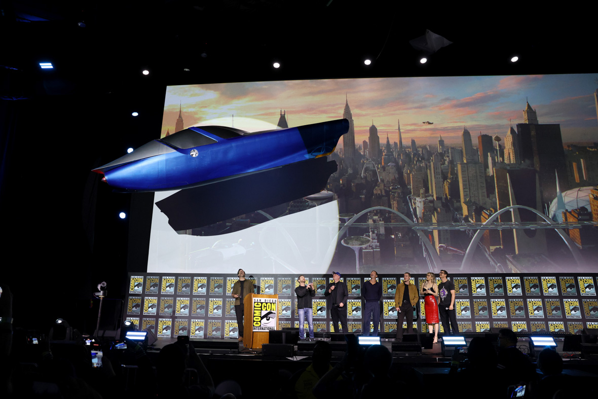 The blue Fantasticar flies overhead as Rob Delaney, Matt Shakman, Kevin Feige, Ebon Moss-Bachrach, Joseph Quinn, Vanessa Kirby,. and Pedro Pascal line up onstage at San Diego Comic-Con.