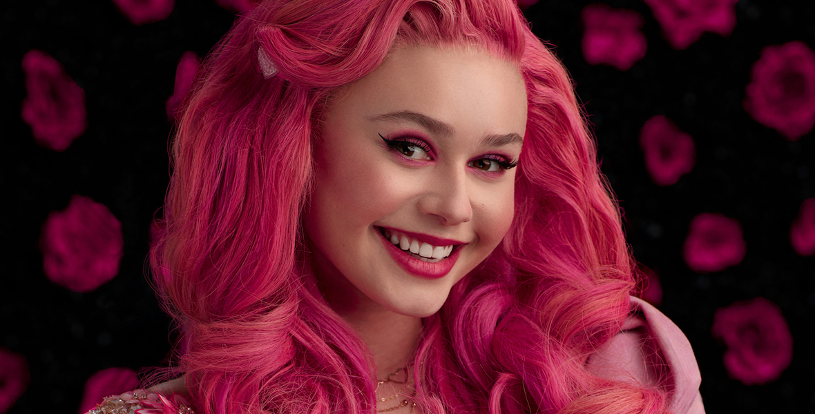 In a promotional image for Disney Channel’s Descendants: The Rise of Red, Bridget, played by Ruby Rose Turner, has wavy pink hair. She is wearing a pink velvet dress and a chain belt, which both feature pink hearts and flowers in their designs.