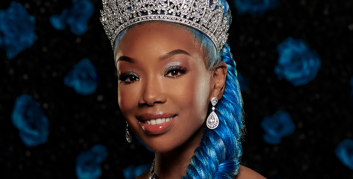 In a promotional image for Disney Channel’s Descendants: The Rise of Red, Cinderella, played by Brandy, wears a blue ballgown, a diamond tiara, diamond earrings, and a diamond necklace. Her blue hair is braided into a fishtail on her left side.