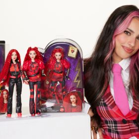 Kylie Cantrall, who plays Red in Descendants: The Rise of Red, poses with four Red fashion dolls. She is wearing a red plaid jacket.