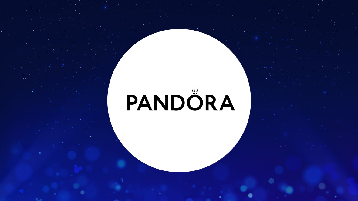 The image features a white circle centered on a dark blue background with subtle sparkling light effects. Inside the circle, the word "PANDORA" is written in bold black uppercase letters. Above the "O" in "PANDORA," there is a small crown symbol, signifying the brand's logo.