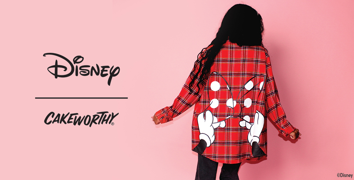 An image for Disney and Cakeworthy collaboration. The image shows a person with long dark hair wearing a red plaid shirt with Mickey Mouse's gloved hands and bow design on the back. The background is pink. The logos for Disney and Cakeworthy are prominently displayed on the left side of the image.