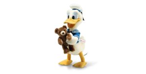 A Steiff plush toy of Donald Duck, dressed in his classic blue sailor outfit and hat, holding a small brown teddy bear in his arms. The plush toy features Donald's characteristic cheerful expression and yellow feet, standing on a plain white background.