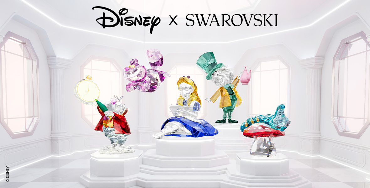 Image for the Disney x Swarovski collaboration. The image showcases a collection of Swarovski crystal figurines featuring Disney characters from Alice in Wonderland. The characters include the White Rabbit, Cheshire Cat, Alice, Mad Hatter, and Caterpillar. The figurines are displayed in an elegant, white, light-filled room with tall windows and classical architectural elements. The Disney and Swarovski logos are prominently displayed at the top of the image.