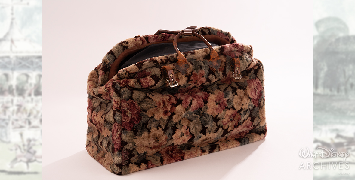 Mary Poppins’ carpet bag is shown. It’s a floral-pattern carpet bag, with leather handles and straps.