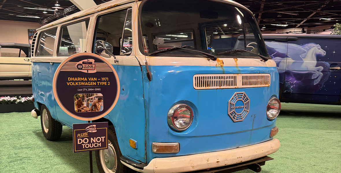 A Dharma bus in worn condition, featuring rust stains and the distinctive Dharma Initiative logo on the front on the show floor.