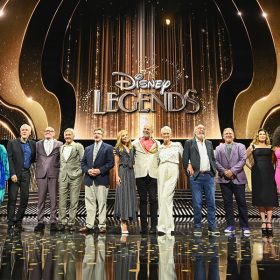 The Disney Legends, Class of 2024, stand in a line onstage at the Honda Center in Anaheim, California, flanked by Mickey Mouse and Minnie Mouse, as part of D23: The Ultimate Disney Fan Event.