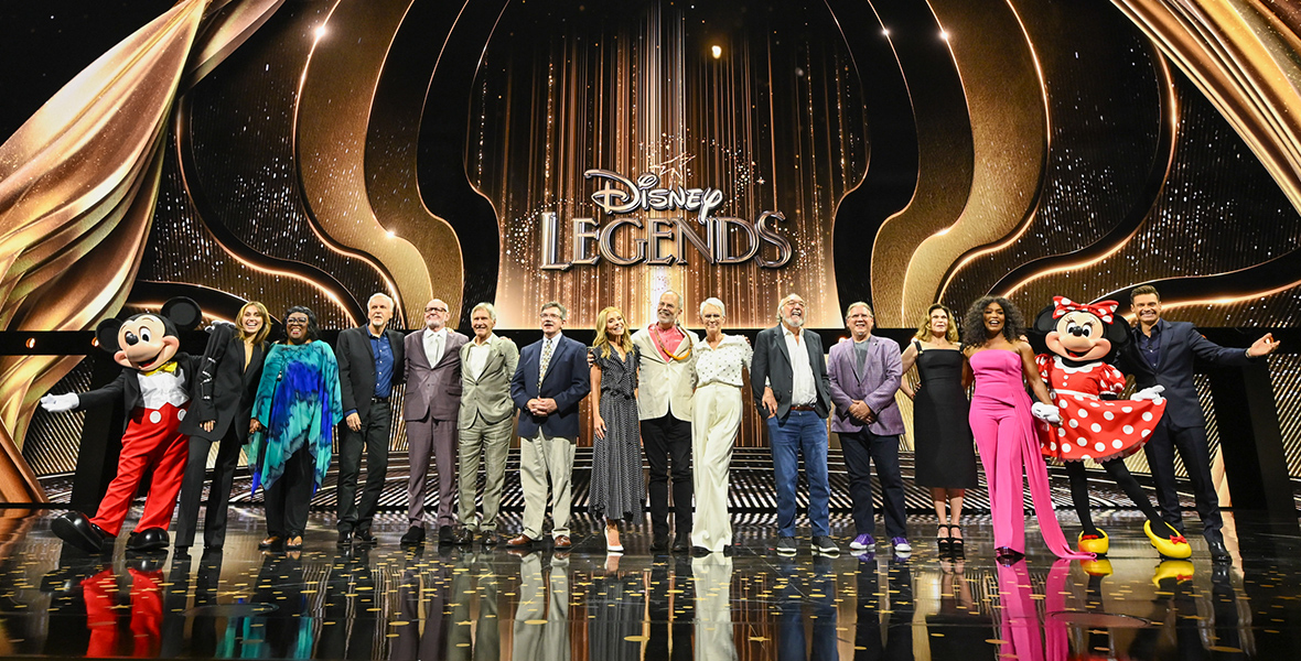 The Disney Legends, Class of 2024, stand in a line onstage at the Honda Center in Anaheim, California, flanked by Mickey Mouse and Minnie Mouse, as part of D23: The Ultimate Disney Fan Event.