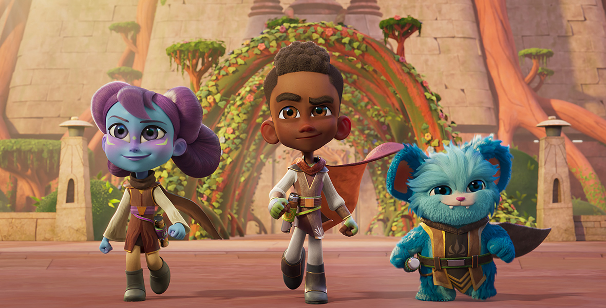 In a scene from “Star Wars: Young Jedi Adventures,” Lys Solay (voiced by Juliet Donenfeld), Kai Brightstar (voiced by JeCobi Swain), and Nubs (a blue, furry member Poobian species voiced by Dee Bradley Baker) are running toward the camera with a determined expression. They’re all wearing Jedi apparel, with deactivated lightsabers attached around their waists. In the background is a tall rock building with archways and greenery. 