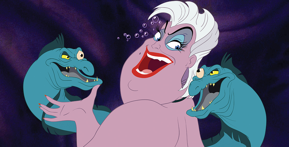 In a scene from The Little Mermaid (1989), Ursula (center), the part-human, part-octopus sea witch (voiced by Pat Caroll), laughs mischievously with two blue eels. She has short white hair and wears red lipstick. Bubbles form above her face as she looks to her left at one of the eels while her right hand lightly touches the eel to her right.