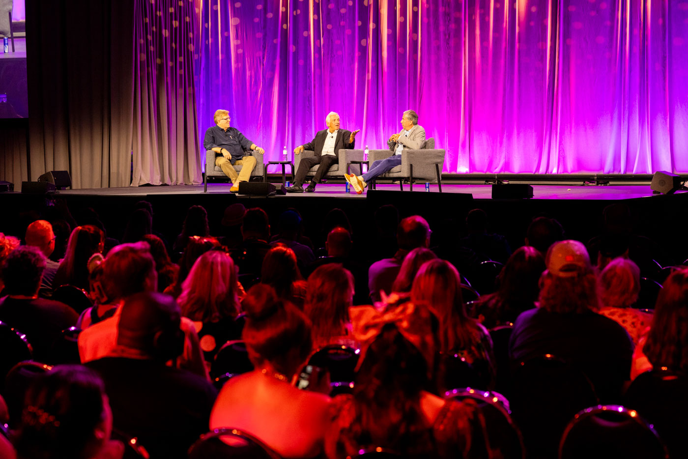 Disney historian Tim O’Day (left), Jeff Sherman (middle), and Greg Sherman (right) on stage during the “Magic Journeys: Memories of the Sherman Brothers” panel at D23: The Ultimate Disney Fan Event 2024. The crowd can be seen in the foreground.