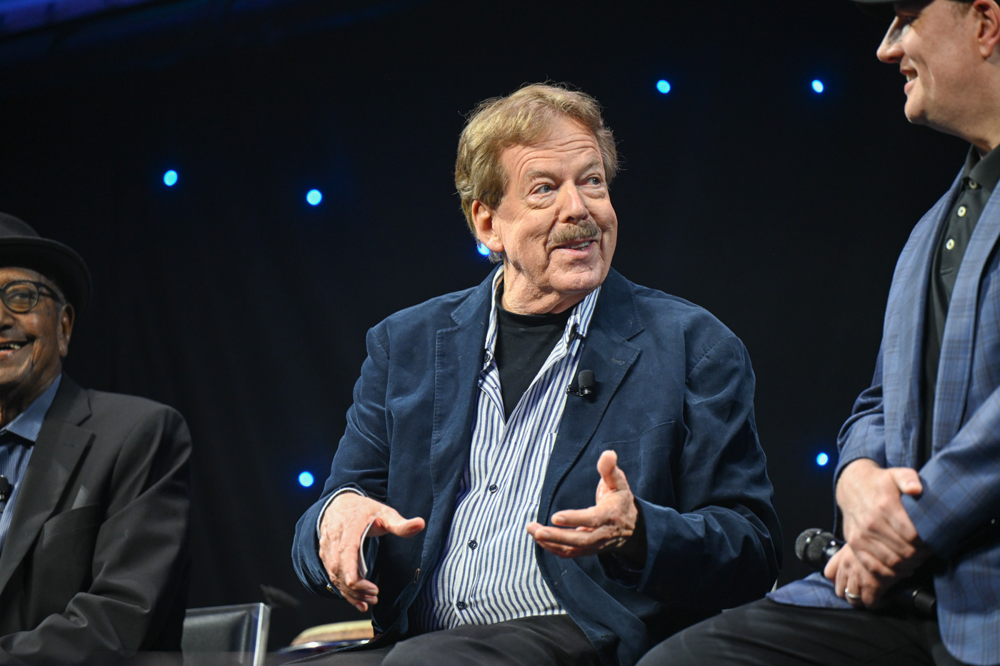 Disney Legend Tony Baxter talks on stage during “Jolly Holiday: A D23 Musical Celebration of Richard M. Sherman” at D23: The Ultimate Disney Fan Event 2024. To his left is Disney Legend Floyd Norman; to his right is Marvel Studios president Kevin Feige.