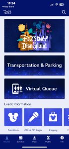A screenshot of the D23 mobile app home screen displaying options for D23 Day at Disneyland, Transportation & Parking, Virtual Queue, and Event Information including Event Hours, Official D23 Stages, and Shopping. The bottom navigation bar includes icons for Discover, Schedule, Maps, My D23, and Info.