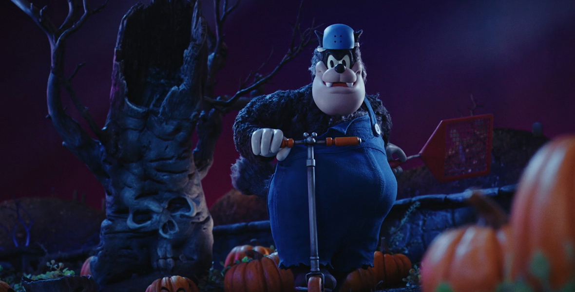 In this scene from Mickey’s Spooky Stories, the stop-motion puppet for Pete stands on a scooter in a pumpkin patch, just in front of a scary-looking tree. In the center of the handlebars for the scooter is a tiny metallic rendition of Mickey Mouse’s head and ears—a hidden Mickey.