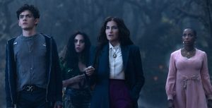 In a scene from Agatha All Along, (from left to right), Teen (Joe Locke), The Green Witch/Rio Vidal (Aubrey Plaza), Agatha Harkness (Kathryn Hahn), and Jennifer Kale (Sasheer Zamata) are standing together in a dark, foggy forest.