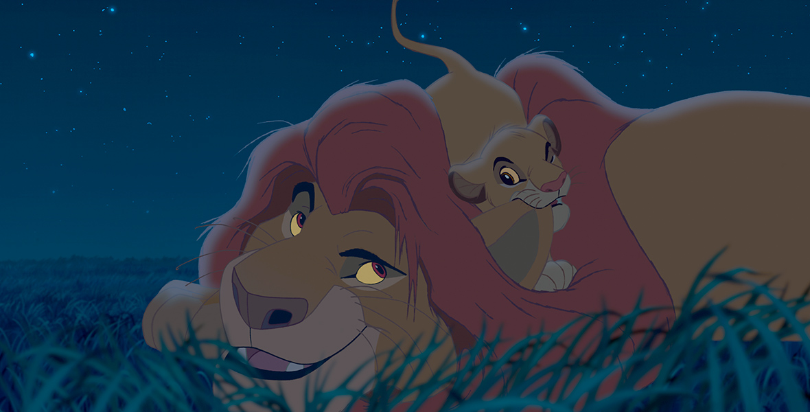 In a scene from Walt Disney Animation Studios' The Lion King, Mufasa relaxes in the grass as his son, Simba, chews on his ear. Stars twinkle in the sky above them.