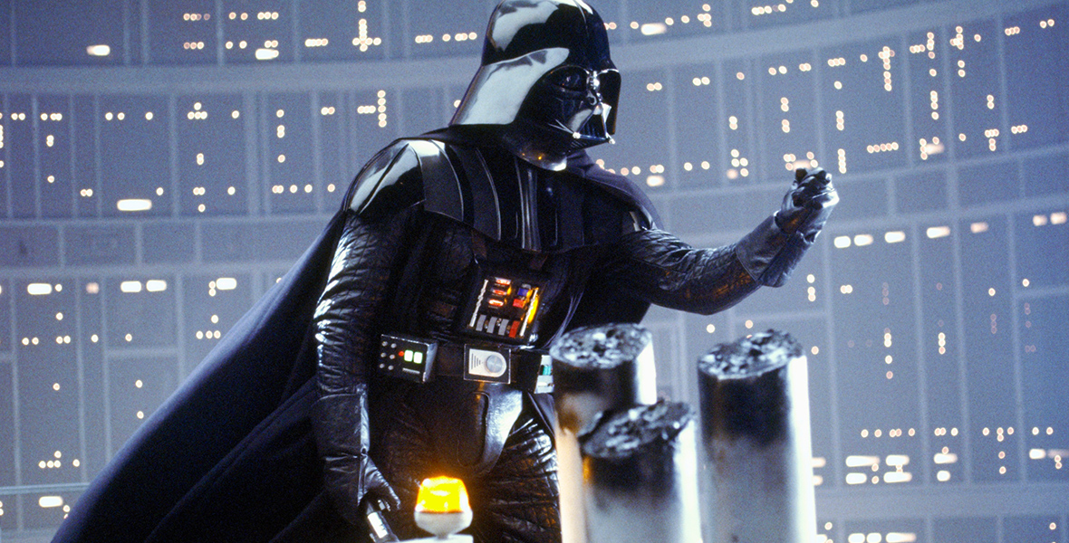 In a scene from Star Wars: The Empire Strikes Back, Darth Vader clutches his left hand as his cape billows in the wind.