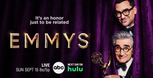 Dan Levy and Eugene Levy peak their heads out from a purple curtain. To the left is text with details on how to watch the 76th Emmy Awards on ABC and stream it on Hulu.