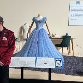 he happy newly engaged couple posing lovingly in front of the live-action Cinderella dress.