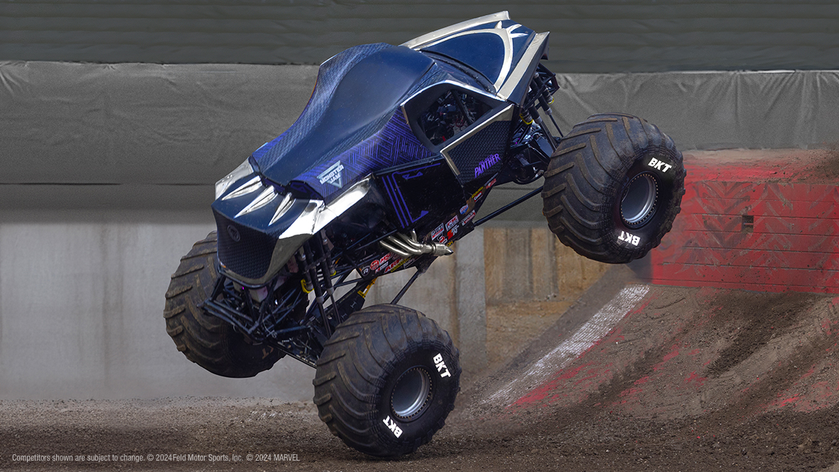 A large monster truck decorated like Black Panther’s suit drives down a steep muddy hill inside the Monster Jam arena. 