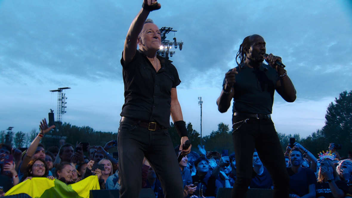 Bruce Springsteen and Curtis King perform together on an outdoor venue.