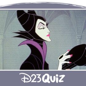 In an image from Sleeping Beauty (1959), Maleficent (voiced by Eleanor Audley) wears a black gown with a high, pointed collar accented with purple details and her signature black horns. She holds a magical golden scepter topped with a glowing orb. Her black raven is perched on the scepter; she is stroking the bird, highlighting a black ring on her index finger. The background features a wall adorned with images of white columns.