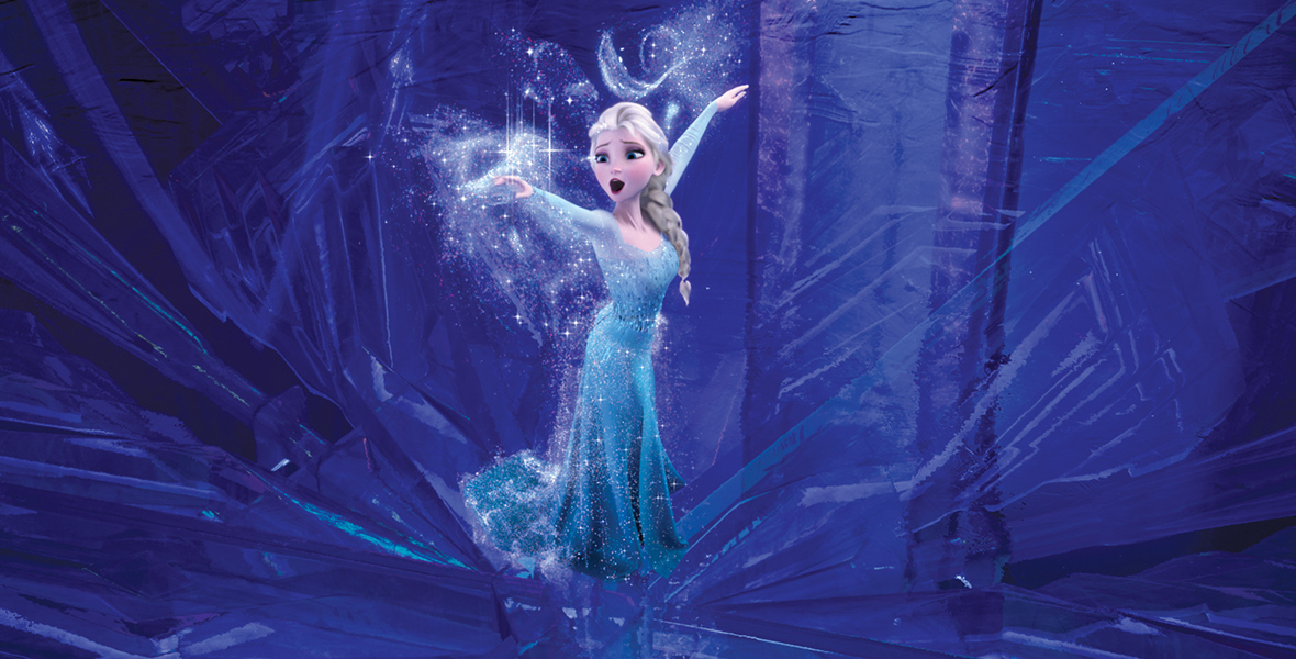 In an image from Frozen, Elsa (voiced by Disney Legend Idina Menzel) stretches her arms out as icy magic swirls around her. She gazes at her right arm while singing. She wears a long-sleeved, light-blue gown, and her hair is styled in her signature braid. The background is a deep blue, featuring intricate ice sculptures.