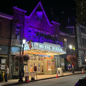 Street view of the town of Sleepy Hollow. The historic Tarrytown Music Hall is centered, prominently, and lit up.