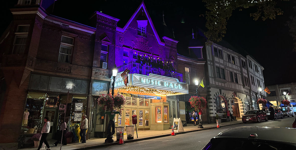 Street view of the town of Sleepy Hollow. The historic Tarrytown Music Hall is centered, prominently, and lit up.