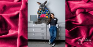 Joanna Pratt, a member of the Walt Disney Archives staff, wearing a dark shirt and gloves, stands next to a large plush aardvark character that is dressed in a colorful Hawaiian shirt and glasses, leaning against a set of gray storage drawers in a well-lit space.