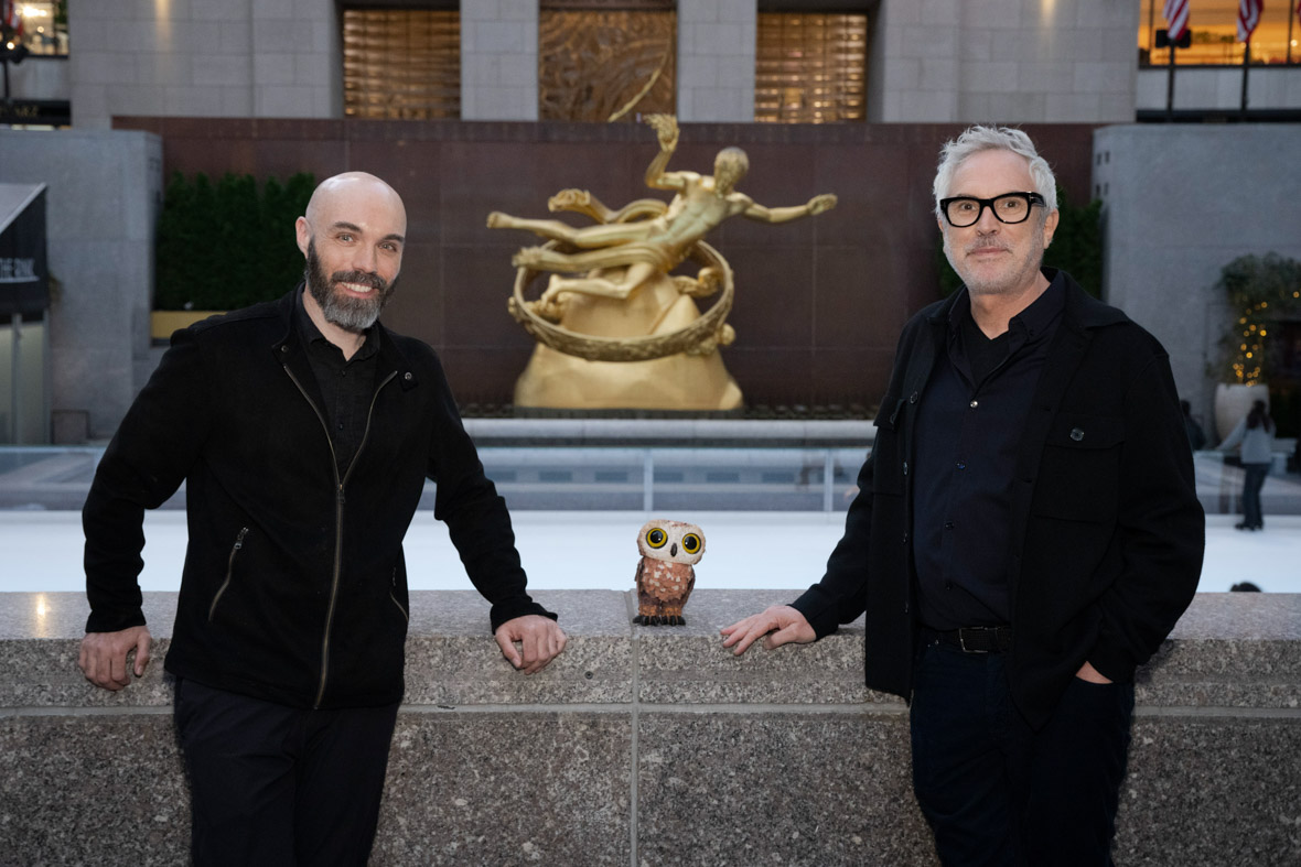 Director David Lowery (left) and producer Alfonso Cuarón (right) pose for a photo in front of the ice skating rink at in Rockefeller Plaza.