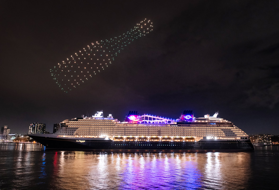 Drones form a champagne bottle above the Disney Treasure cruise ship.