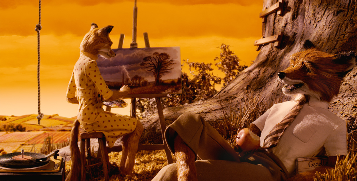 In a scene from Fantastic Mr. Fox, Mrs. Fox (voiced by Meryl Streep), an anthropomorphic fox, sits on a stool, painting a canvas that depicts trees under a cloudy sky with flashes of lightning. She wears a mid-sleeve yellow wrap dress with small red apples. Nearby, Mr. Fox (voiced by George Clooney), an anthropomorphic fox, lounges by a tree, holding a bitten apple in his right hand. He sports a short-sleeved white shirt, a striped tie, and khaki pants. The background features a gradient sky in hues of yellow and orange, complemented by fields in matching tones