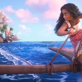 In an image from Walt Disney Animation Studios’ Moana 2, Moana (voiced by Auli‘i Cravalho) is on her canoe, in the ocean, looking back at a flotilla of Kakamora. She is holding ropes in both hands while glancing over her shoulder, with a determined look on her face; another rope connects the canoe to the Kakamora.