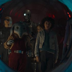 In a scene from Star Wars: Skeleton Crew, KB, played by Kyriana Kratter, Neel, played by Robert Timothy Smith, the droid SM-33, voiced by Nick Frost, Fern, played by Ryan Kiera Armstrong, and Wim played by Ravi Cabot-Conyers, huddle around an opening.