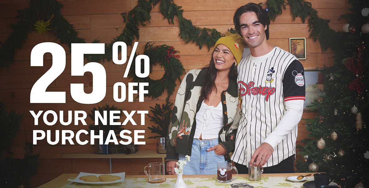 Two models, one woman and man, are adorned with BoxLunch Disney apparel, and smile at the camera. A backdrop of a holiday wreath and other evergreen is behind them with copy that reads “25 % off your next purchase”