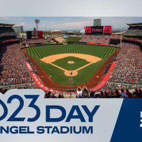 A full image of Angel Stadium, from the top level, with a view behind home plate. The stadium is filled with fans, mostly dressed in red. On the field, there is a player on the pitching mound and behind home plate. The Los Angeles Angels’ logo, a halo-topped capital “A,” is on the right. The bottom of the image reads “D23 Day at Angel Stadium” in dark blue against a gray background and “May 25, 2025” in gray and white text against a blue background.