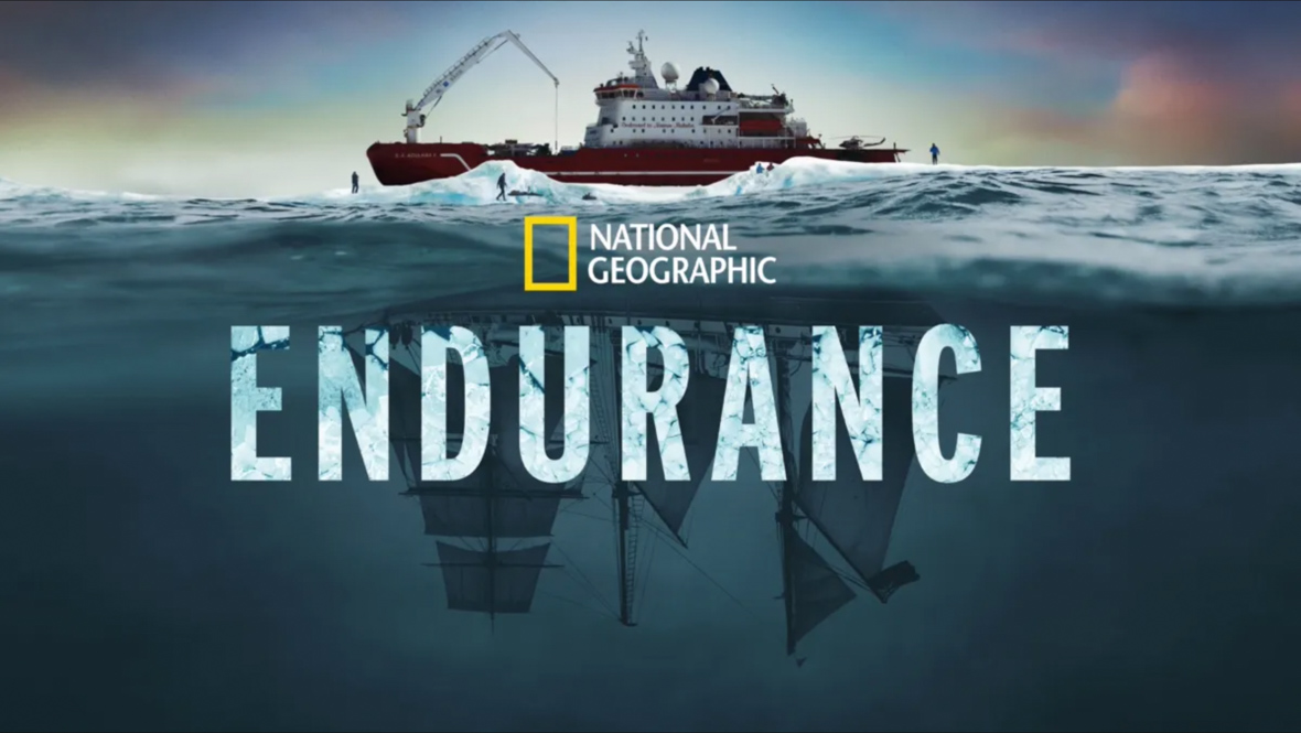 The key art image for National Geographic’s documentary Endurance; a modern ship is seen at the top of the image, floating on water, and the shadow of an old-fashioned schooner-type ship mirrors the modern one below it. The National Geographic logo and the title of the film are seen at center.   