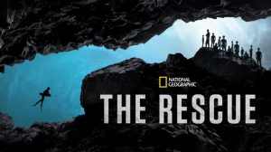 A key art image for National Geographic&rsquo;s The Rescue. At left, a solo diver is making their way through a narrow cave-like space underwater. At right, a group of people is standing in another part of this &ldquo;cave,&rdquo; waiting for the diver to arrive. Below the group and set against a rock-style background is the National Geographic logo and the title of the film.