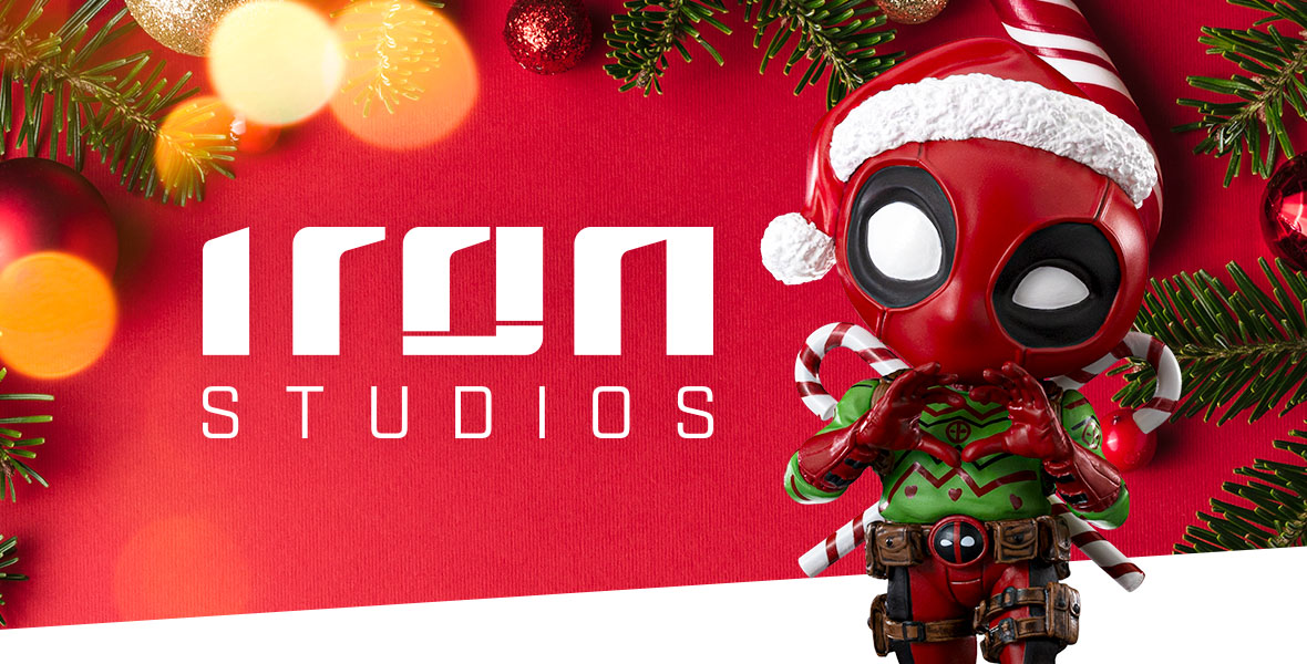 A figurine of Deadpool from Iron Studios is decked out with a Santa hat, green and red festive sweater with interlocked candy cakes in the background.