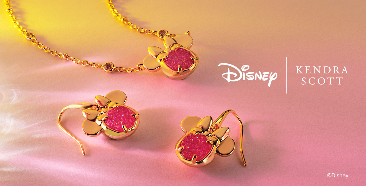 A set of Minnie Mouse jewelry, a gold and pink-jeweled necklace and pair of earrings are seen against a pink background with the copy “Disney I Kendra Scott” at Right and @Disney at bottom right.