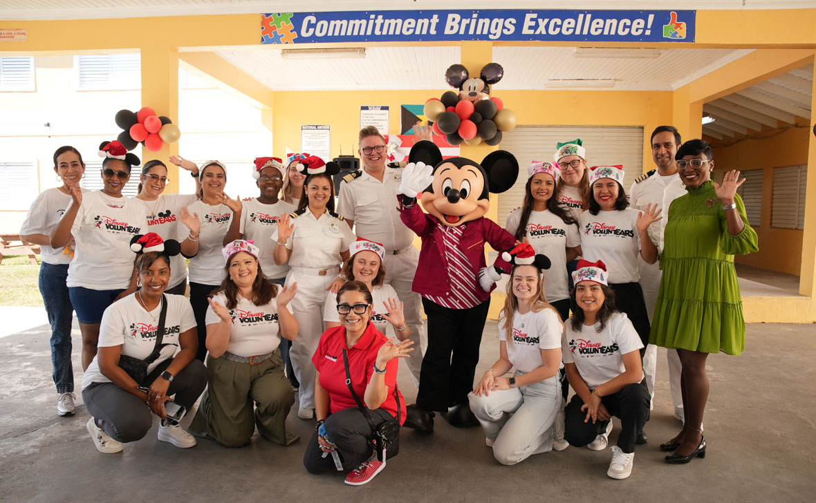 In an image from the Mickey Around the World Toy Drive Tour, Mickey Mouse poses with teachers and Disney VoluntEARS.  