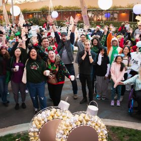 D23 Members cheer in excitement surrounded by festive holiday decorations.